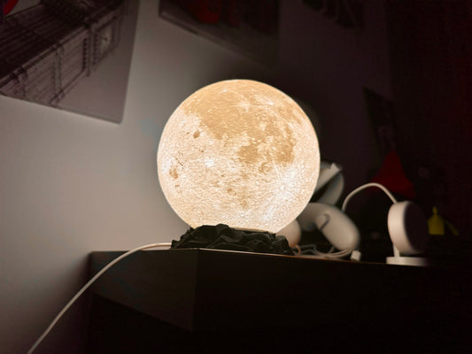 Lampe in Mond Optik auf schwarzen Sockel in Felsen Optik